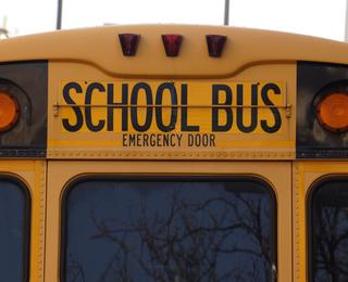 Back view of a yellow school bus with emergency door sign.