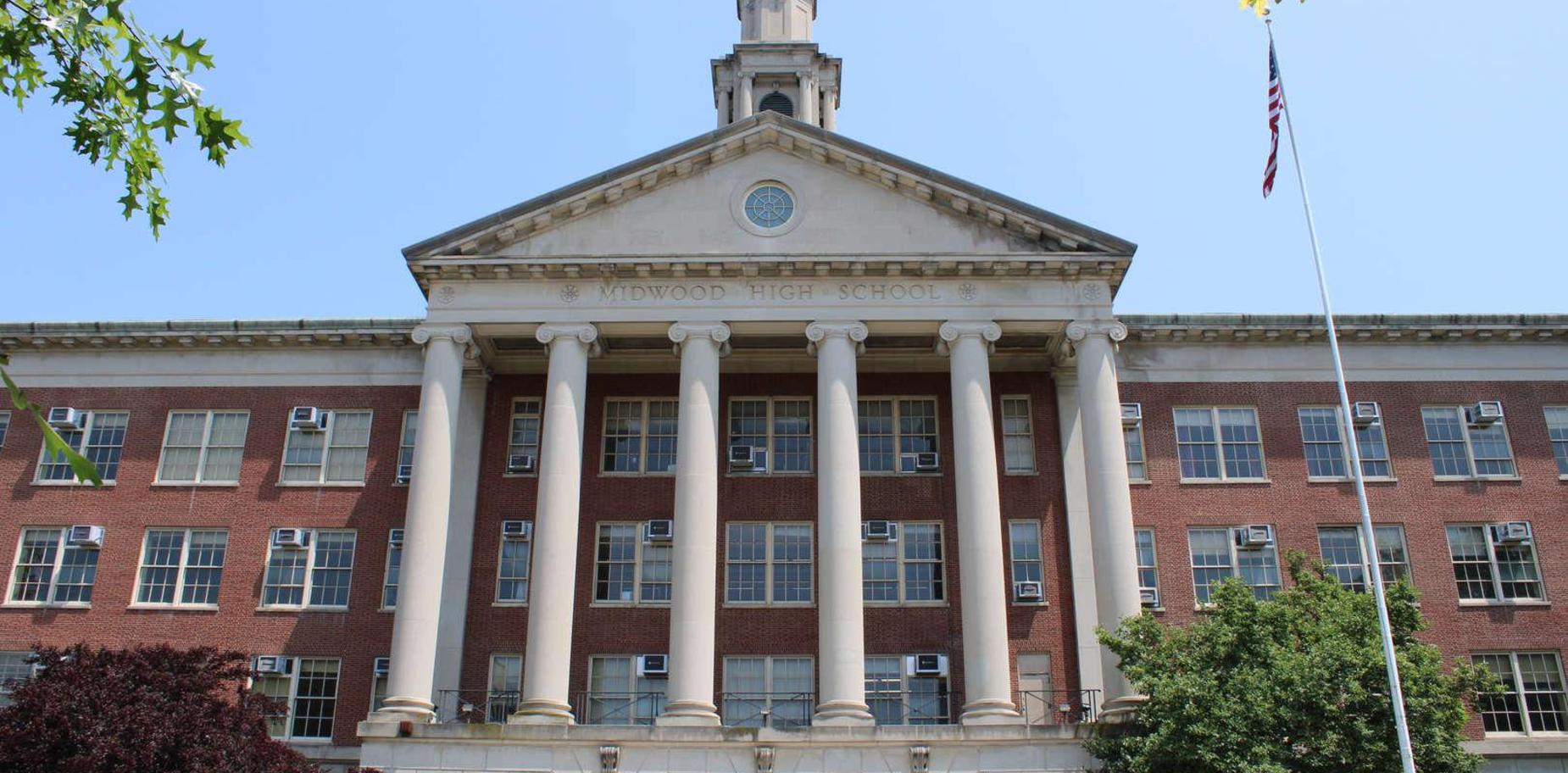 Facade of Midwood High School with large columns and windows under a clear blue sky.