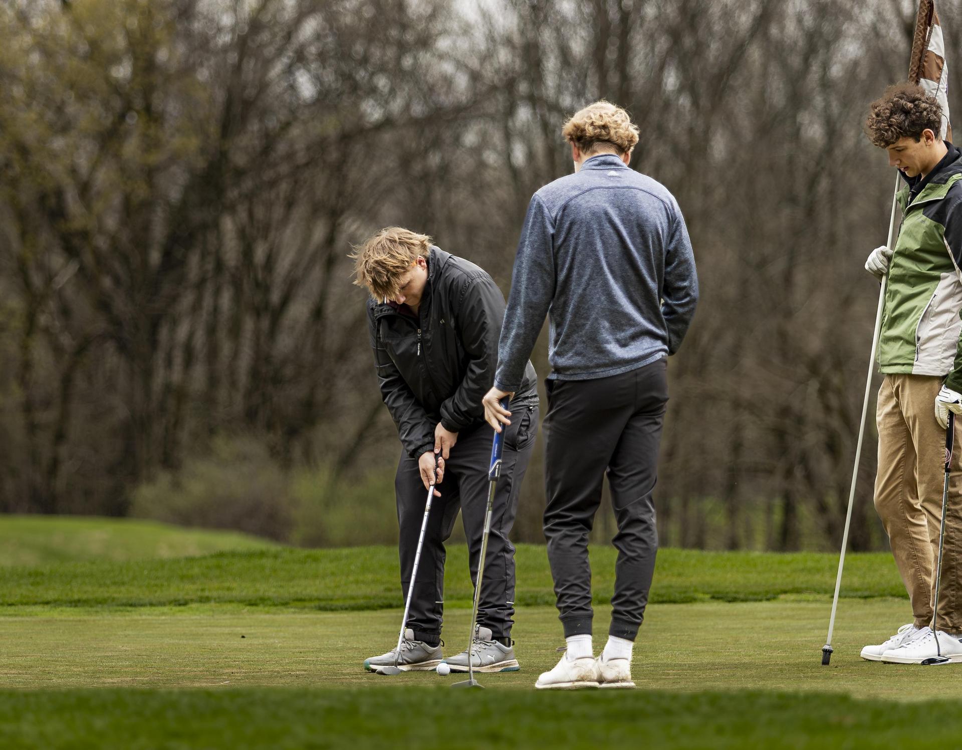 Three golfers putting the ball