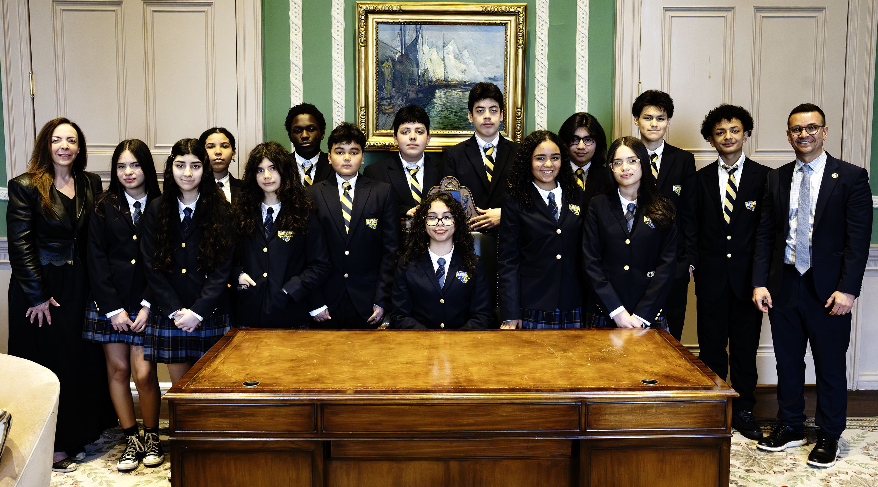 Group of students and adults in formal attire posing in an elegant room.