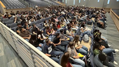A large group of students seated in an auditorium for orientation.