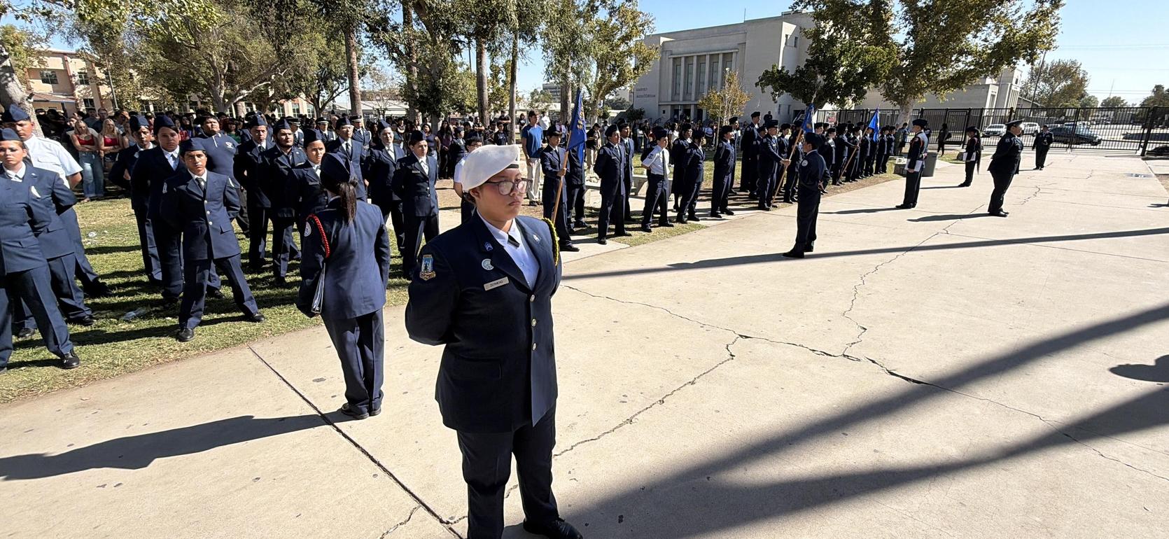 A large group of uniformed individuals standing in formation outdoors.