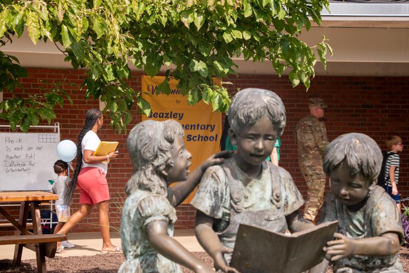 A statue of students reading rests on the lawn of Beazley Elementary as families visit the campus.