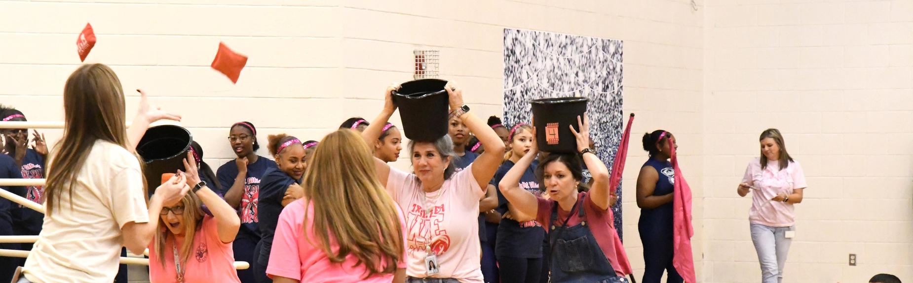Participants engaging in a fun team challenge with buckets during a school activity.