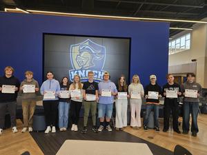 group of students holding up awards in front of knight head