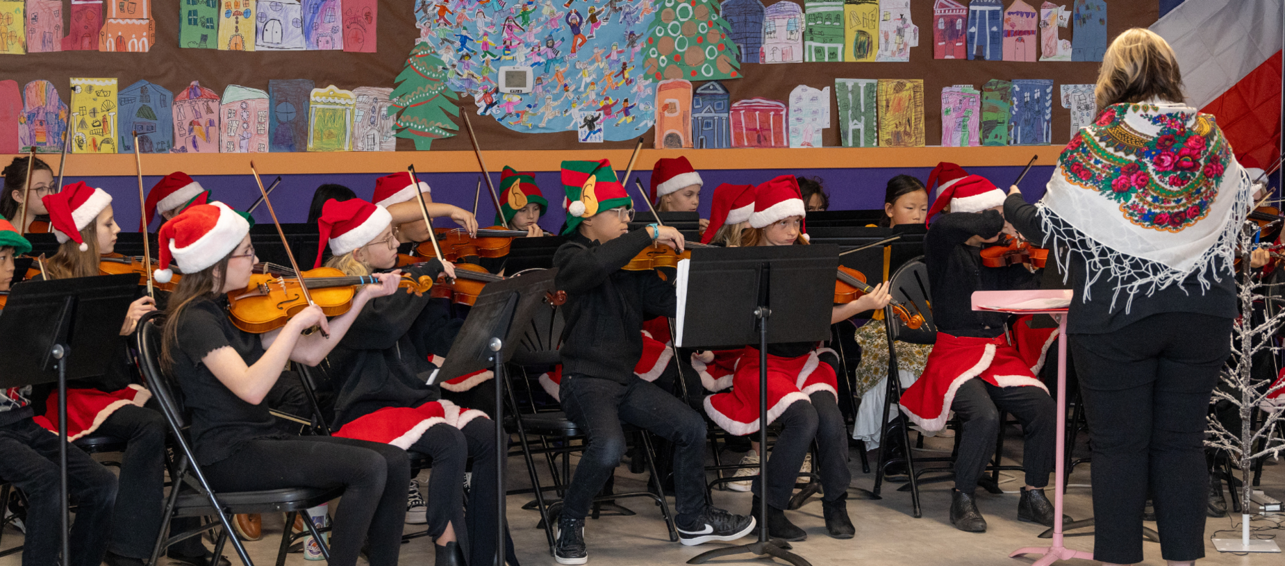 A youth orchestra performs holiday music while wearing Santa hats.