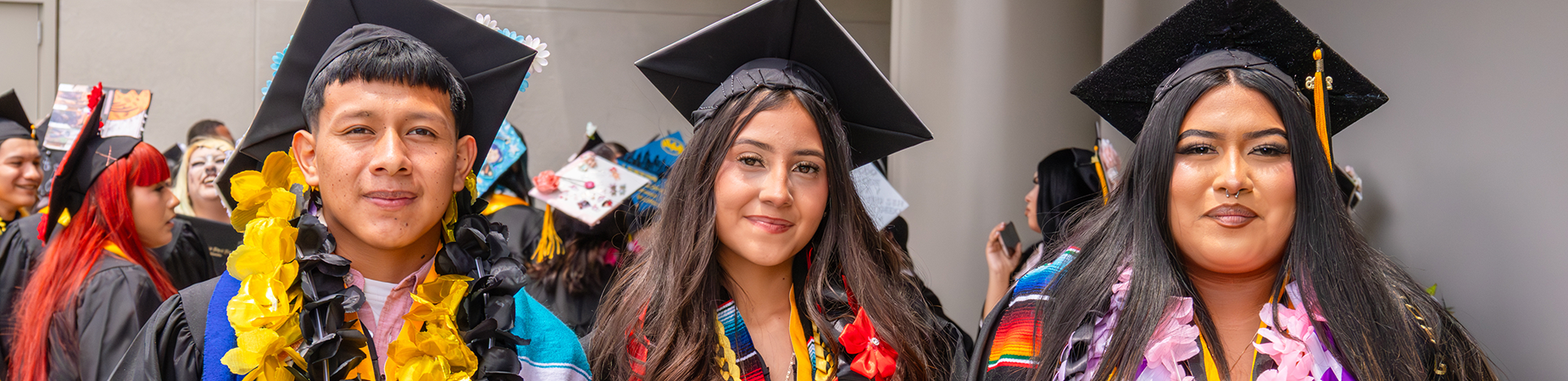 Three high school graduates, a young man and two young women, in caps and gowns