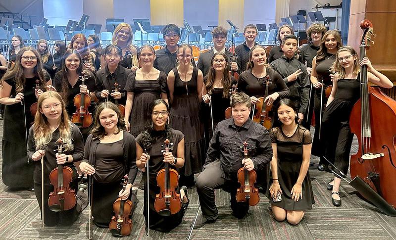 a group od students wearing black and holding strings instruments