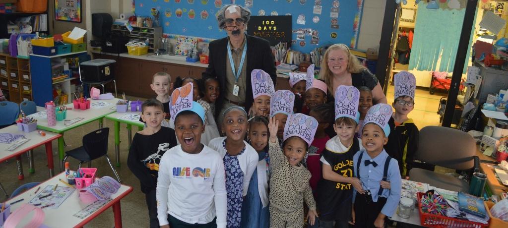 class of students wearing "100 Days Smarter" paper hats pose for the camera