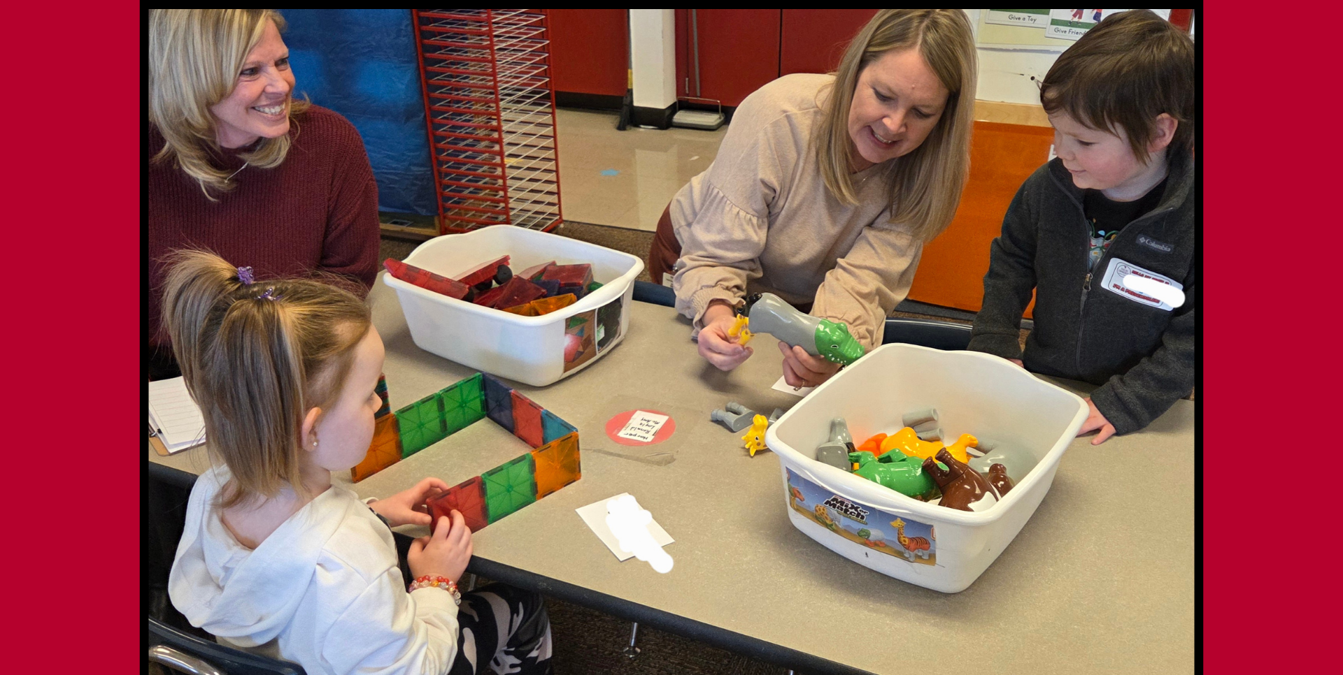 Adults and children engaged in play with toys at a table.