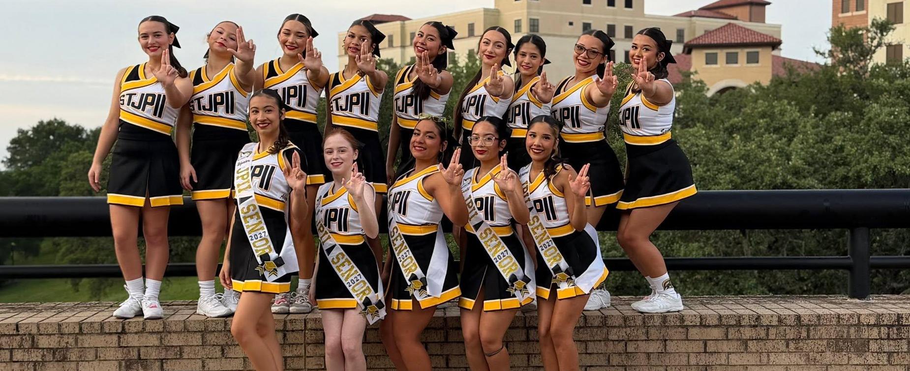 A group of cheerleaders posing together outdoors, all wearing uniforms.