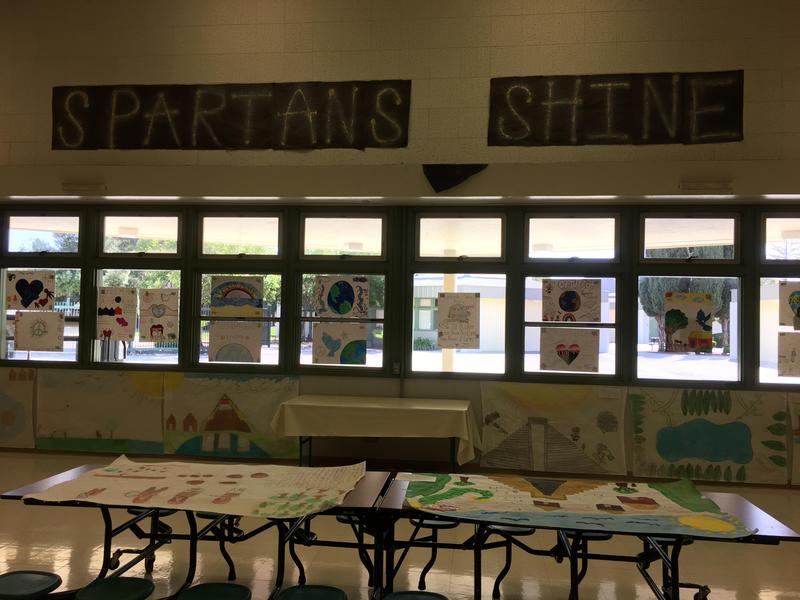 Art projects displayed on tables and windows in a cafeteria