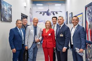 District and CSBA leaders pose in the aviation hallway at Porterville Military Academy, with a fighter jet mural visible in the background.