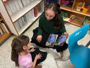 a seventh grade girl read her Gadol picture book to a kindergarten student.