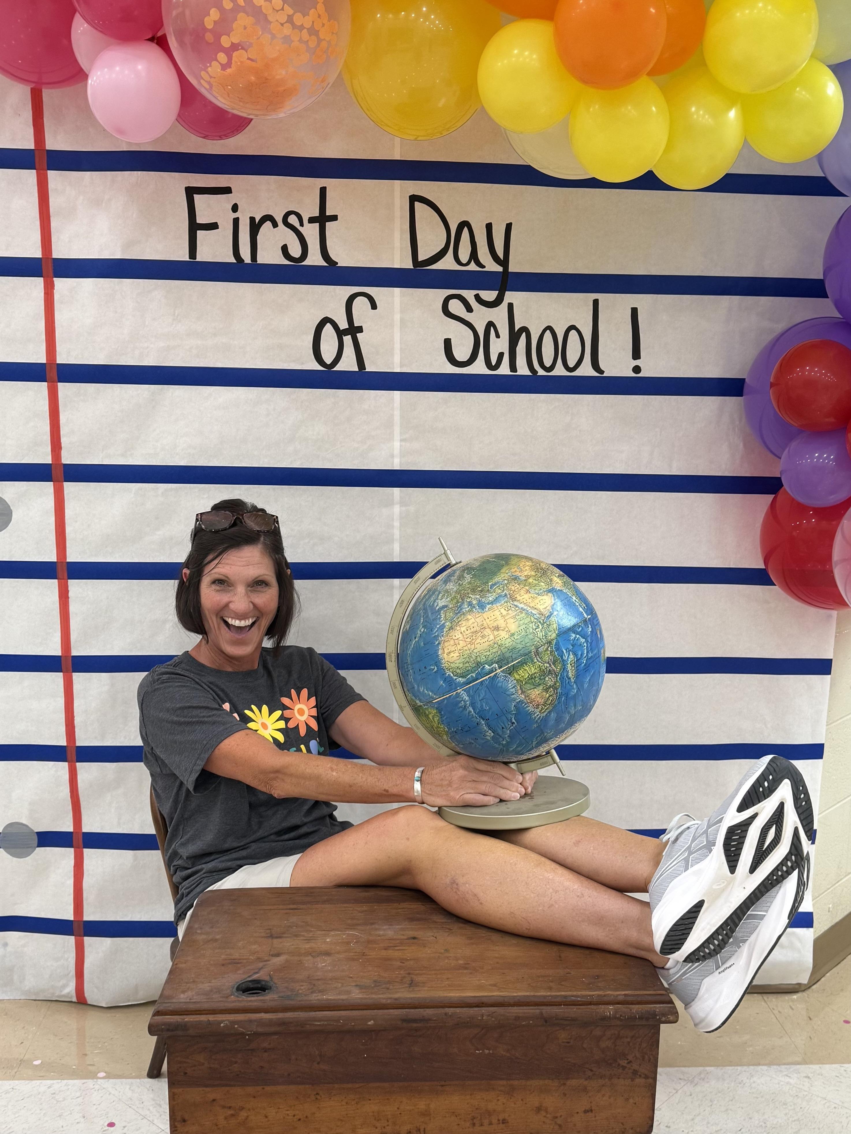 Mrs. PE sitting with her feet on a desk with the world in her hands.