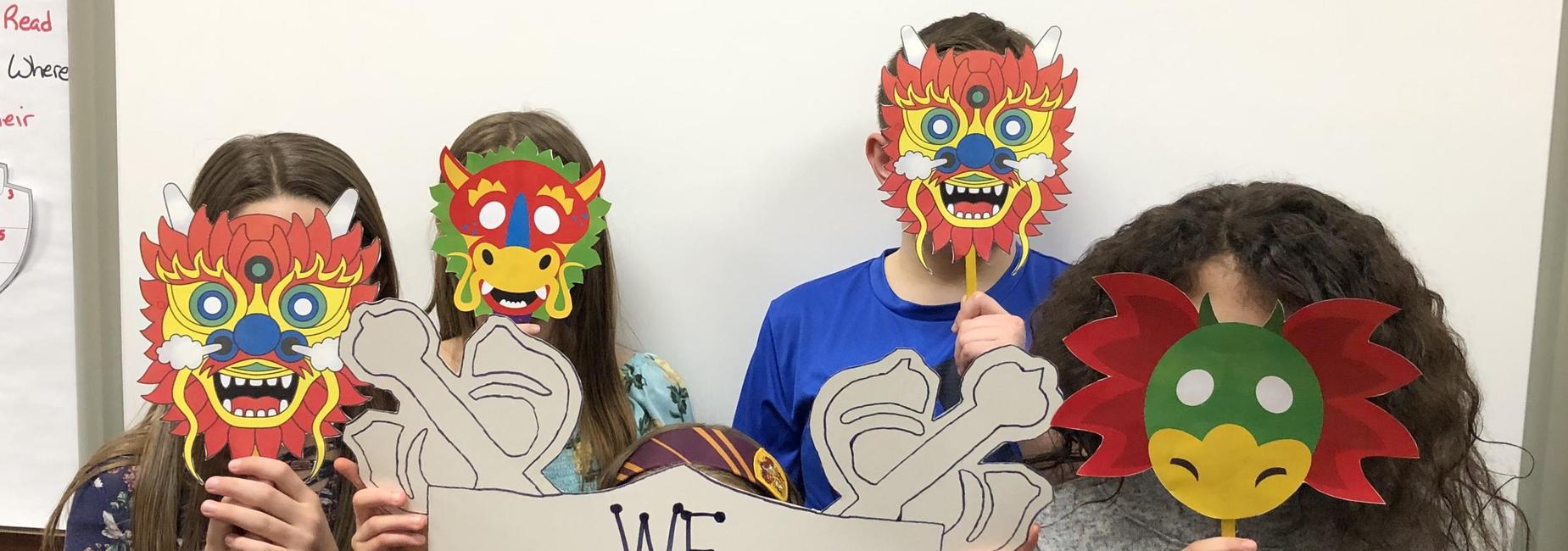 Students holding dragon masks in front of face