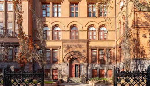 Historic brick school building with arched windows and entryway.