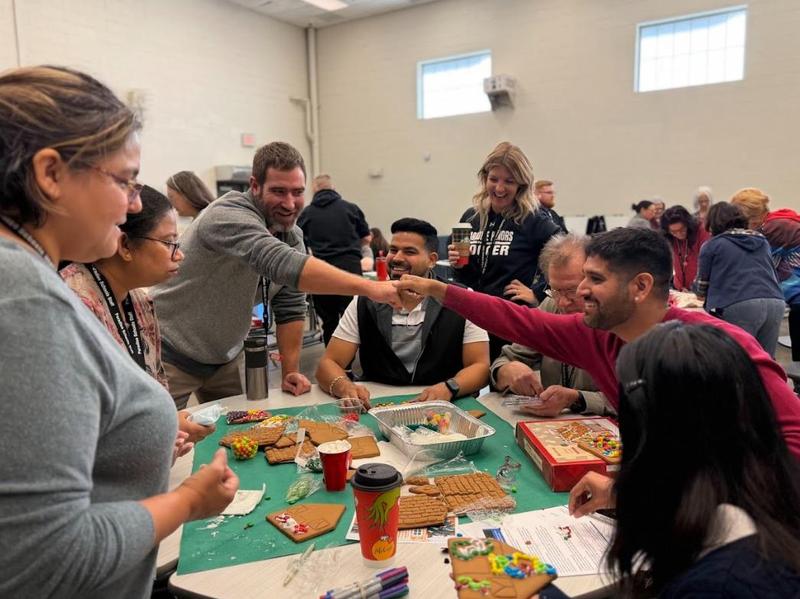 teachers building a gingerbread house together and laughing
