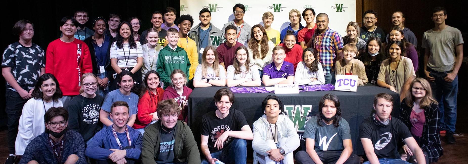 large group of teens on the stage at the athletics and fine arts signing day ceremony