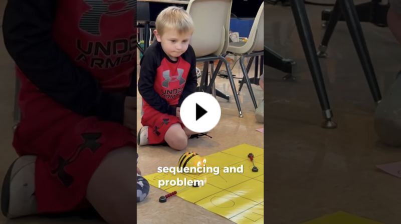 YouTube thumbnail of a young blonde student watching a bee-shaped robot move on a large grid.