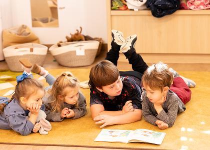 Children of varying ages reading a book on the floor