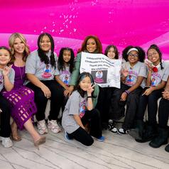 Group of children and adults posing together with a thank-you sign.