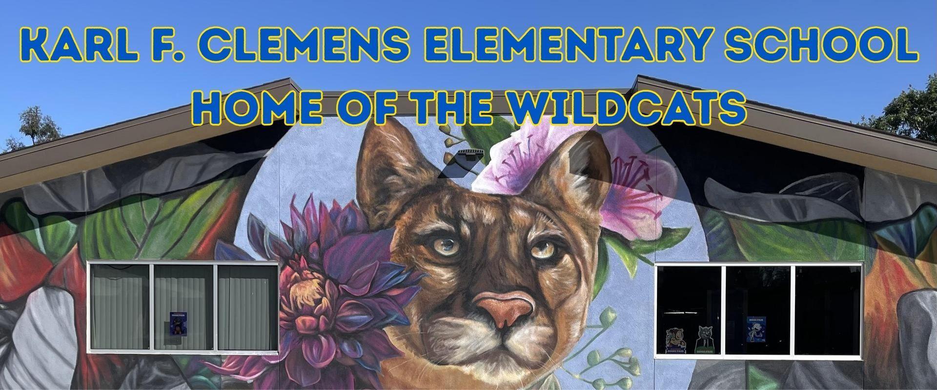 Mural of a wildcat surrounded by flowers on a school building.
