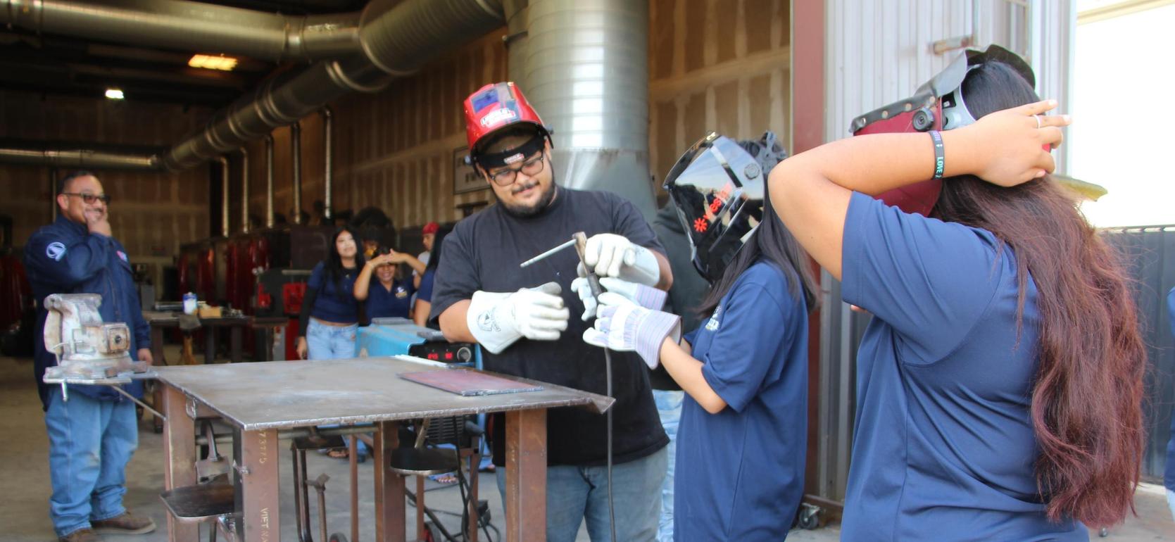 Group of people in a workshop, learning welding techniques.