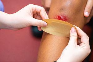 Nurse putting a bandage on a scraped knee