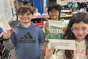 Three students hold up notes that they selected to give staff