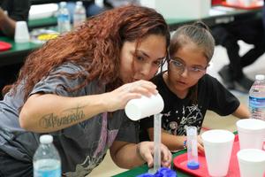 a lady and young child measure science experiment ingredients carefully