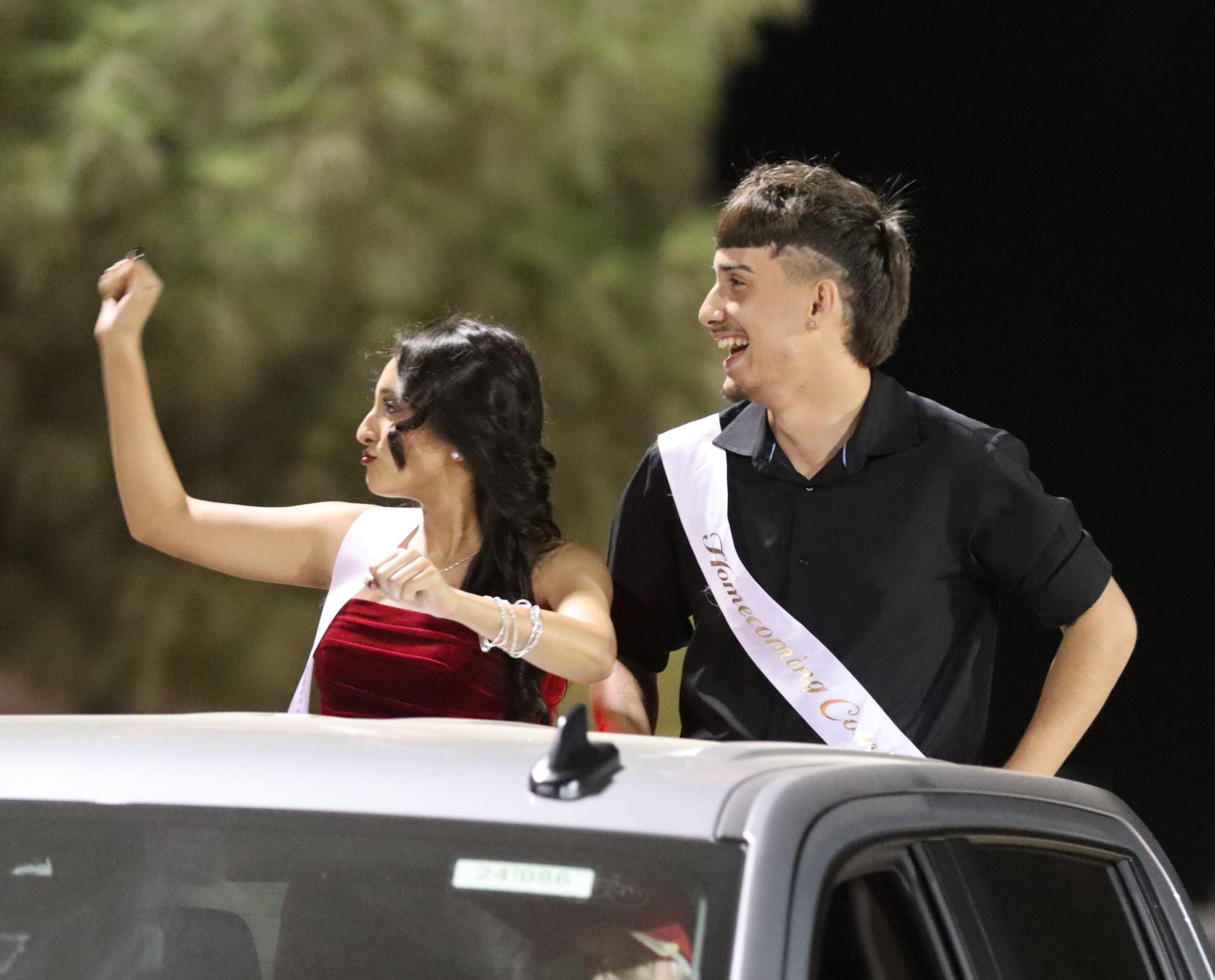 homecoming king and queen candidates entering the stadium in trucks