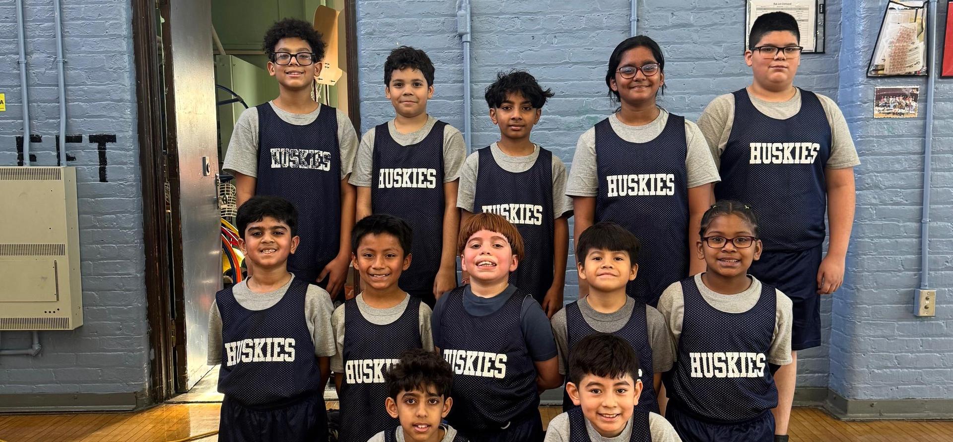 Group of young basketball players wearing jerseys with 'Huskies' written on them.