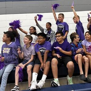 Students sitting in stands cheering on new purple house members.