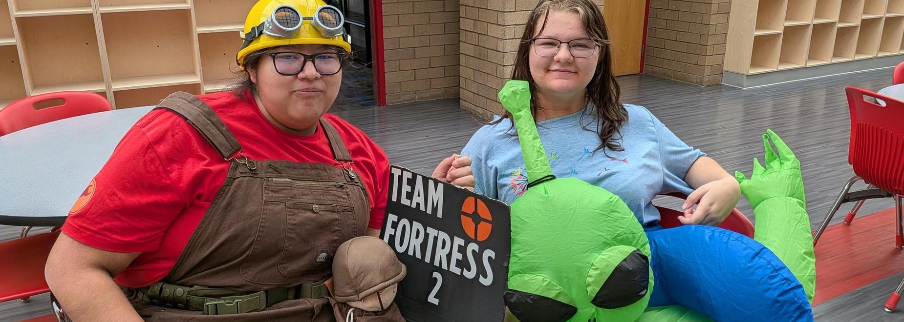 Two cosplayers dressed as Team Fortress 2 characters posing with an inflatable alien.
