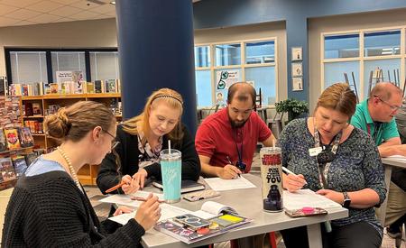 Participants engaged in a collaborative writing session at a library table.