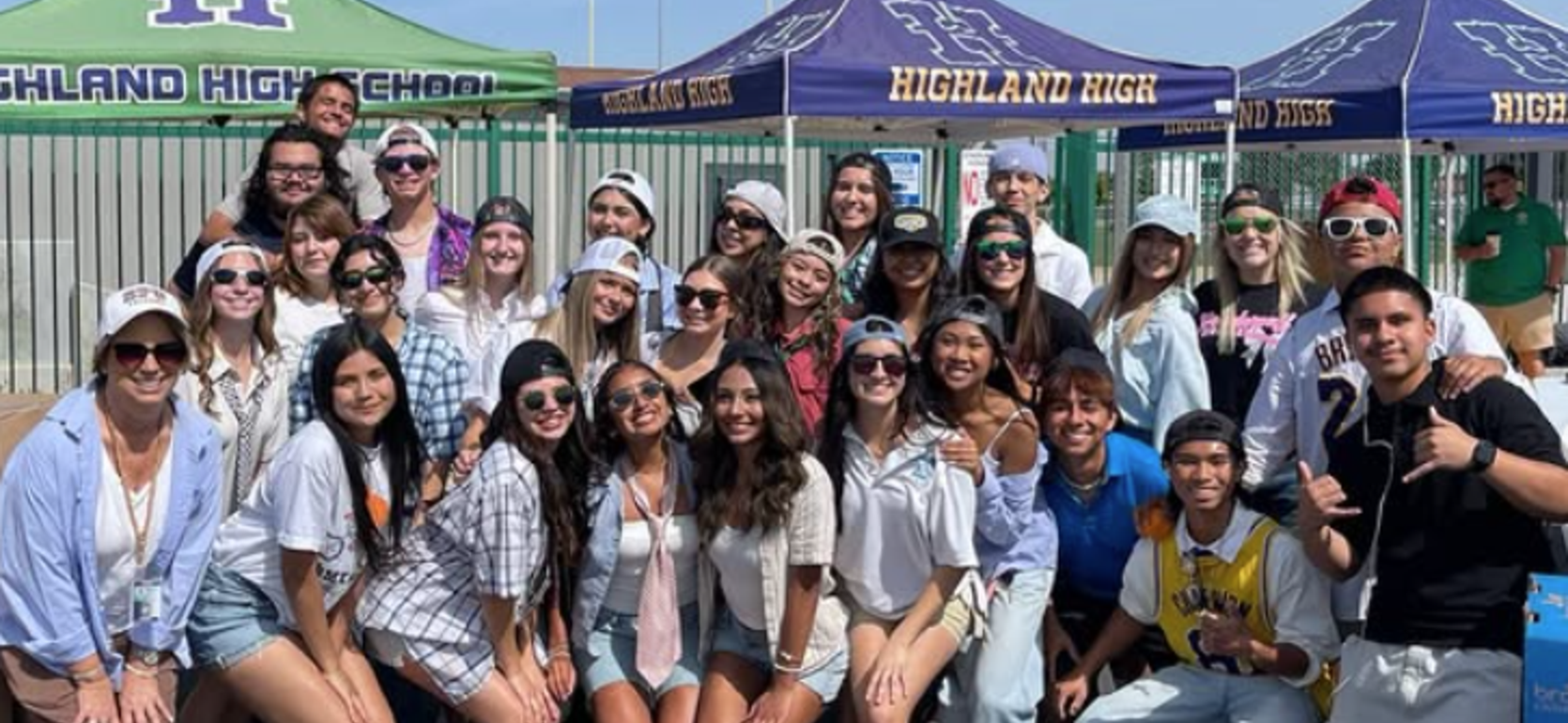 Large group of students in casual outfits, celebrating outdoors under tents.