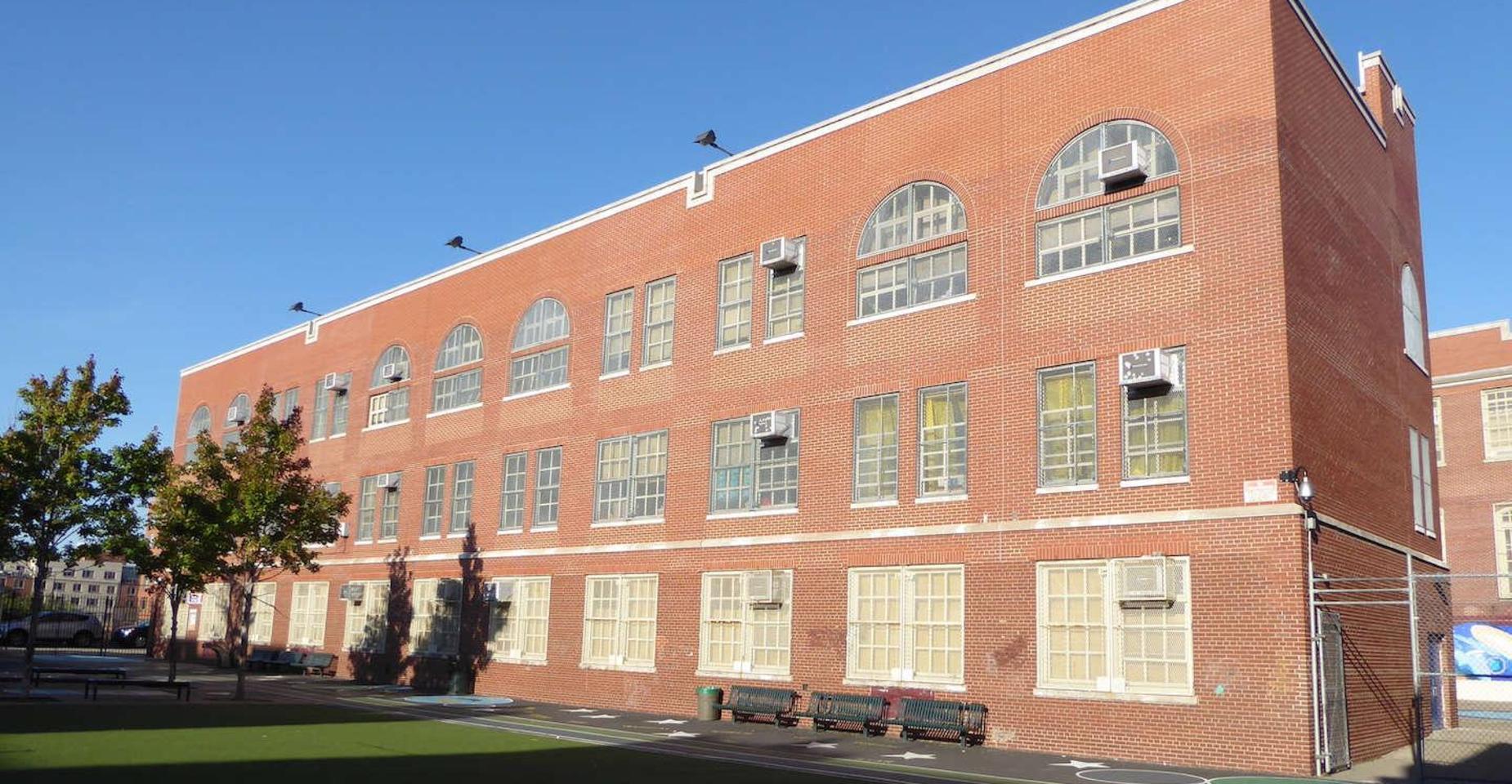 Brick school building showcasing windows and surrounding greenery.