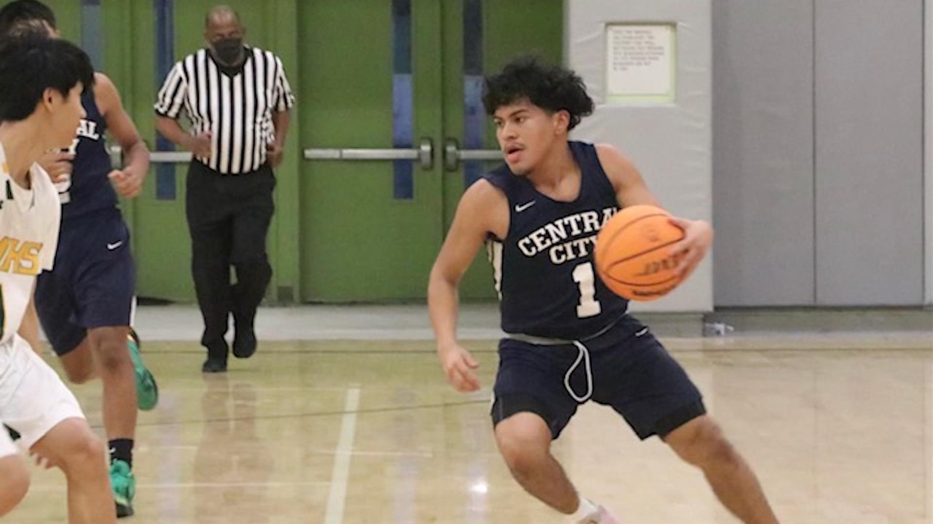 A basketball player dribbles the ball during a game, with opponents nearby.