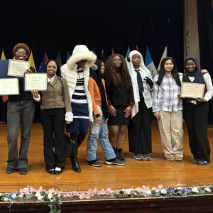 CMSA Speech and Debate students stand on a stage holding awards and certificates after a debate tournament.