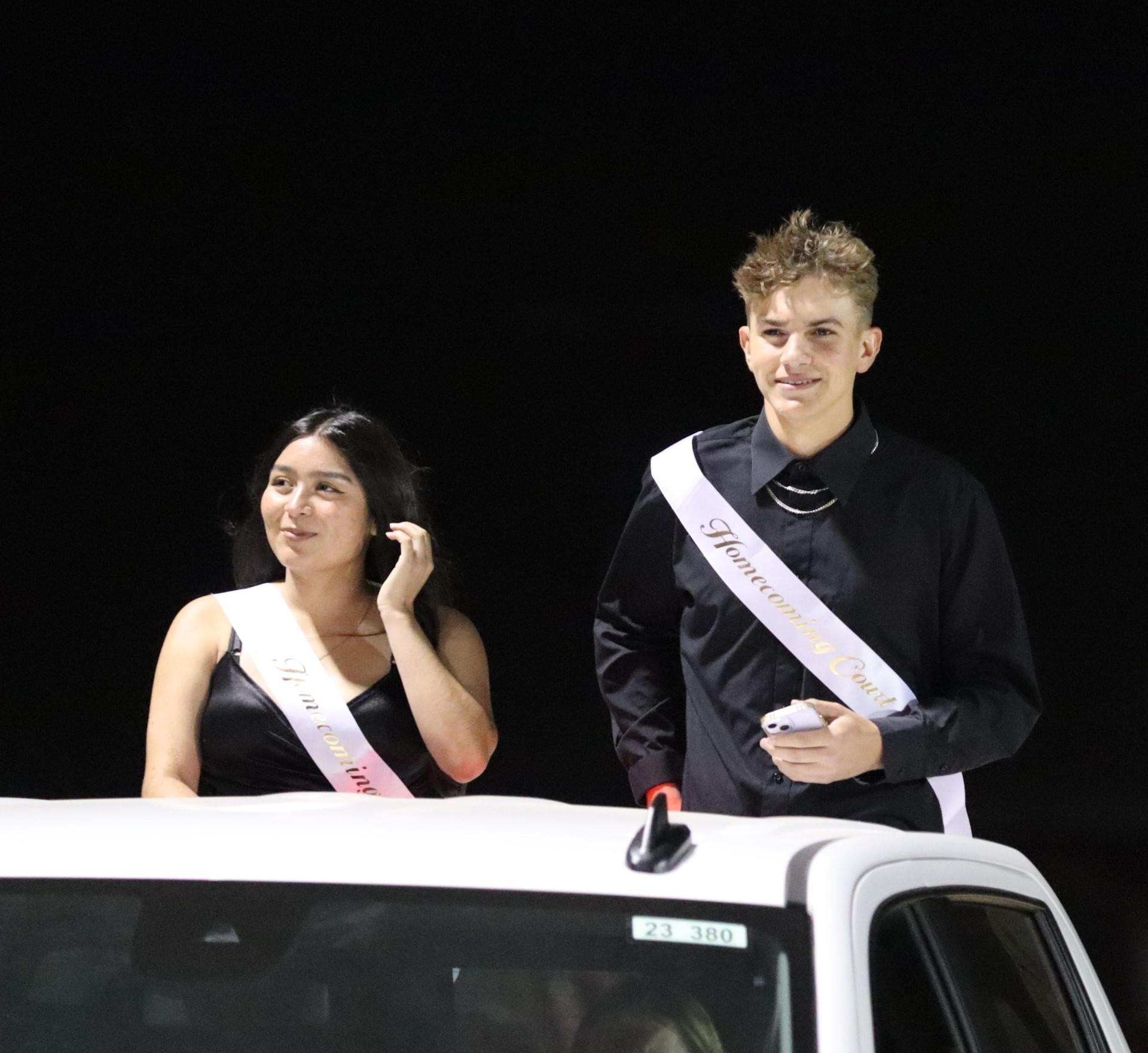 homecoming king and queen candidates entering the stadium in trucks