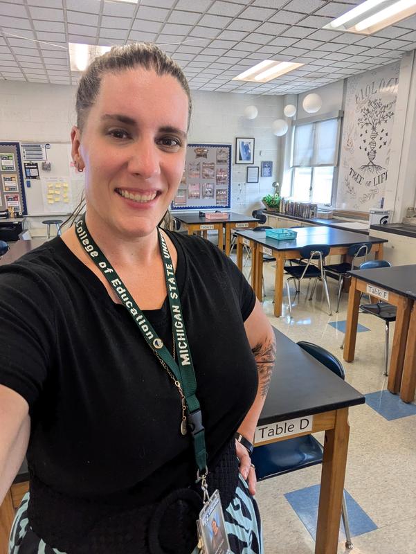 smiling female in a classroom with desks.
