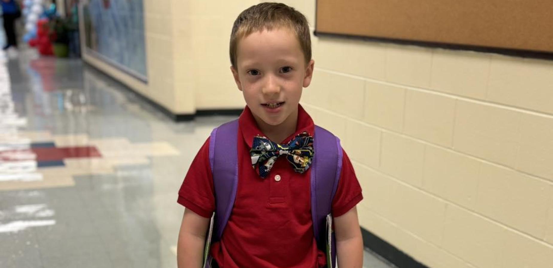 Student standing in hallway wearing bowtie with his uniform