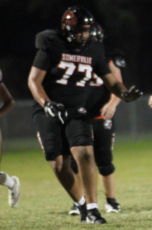 A football player in a black uniform is preparing to block or move on the field.
