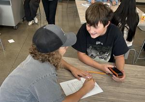 A student with a handheld air-quality sensor and a student with a worksheet prepare to conduct air-quality experiments.
