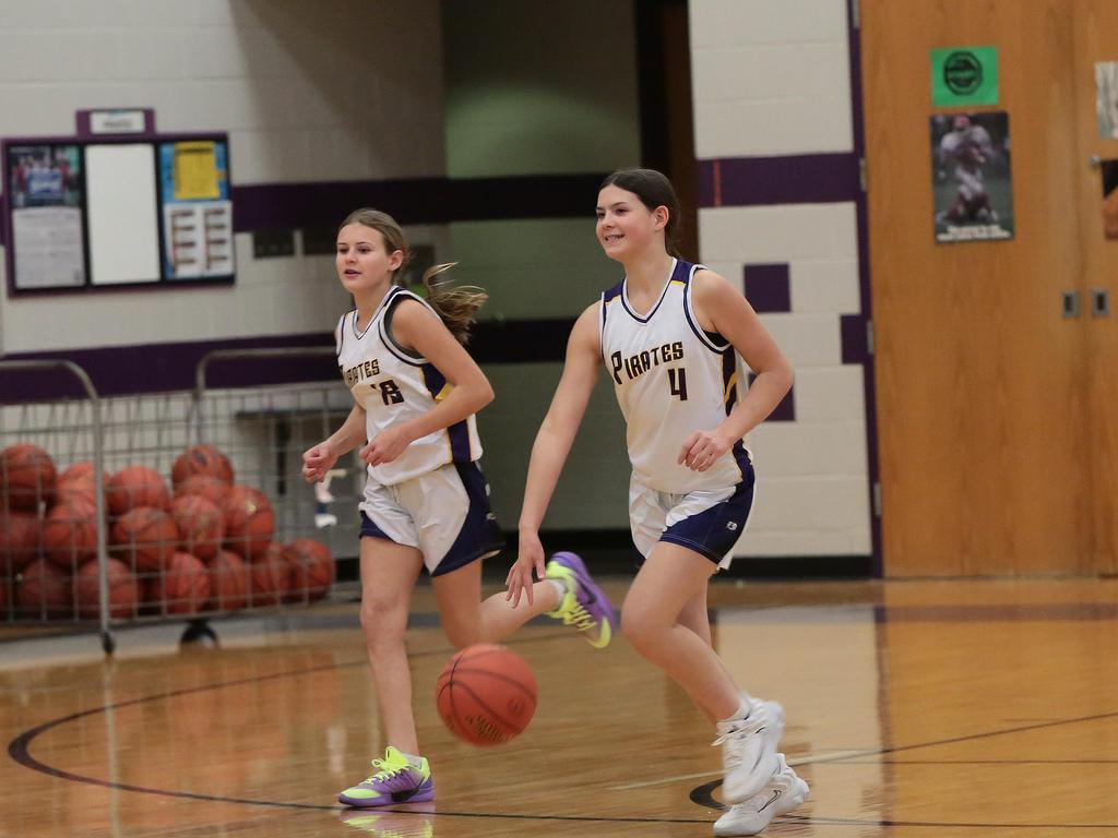 Two basketball players running on the court, with one dribbling ball.
