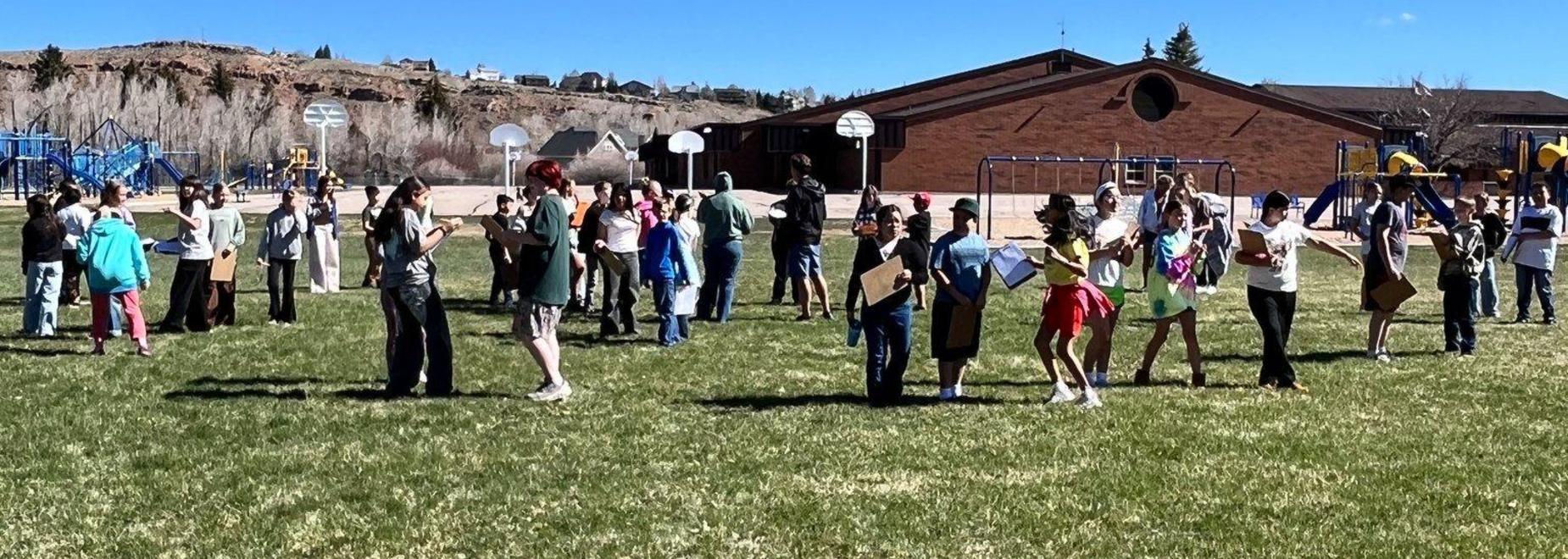 A group of children and adults participating in an outdoor activity on a grassy field.