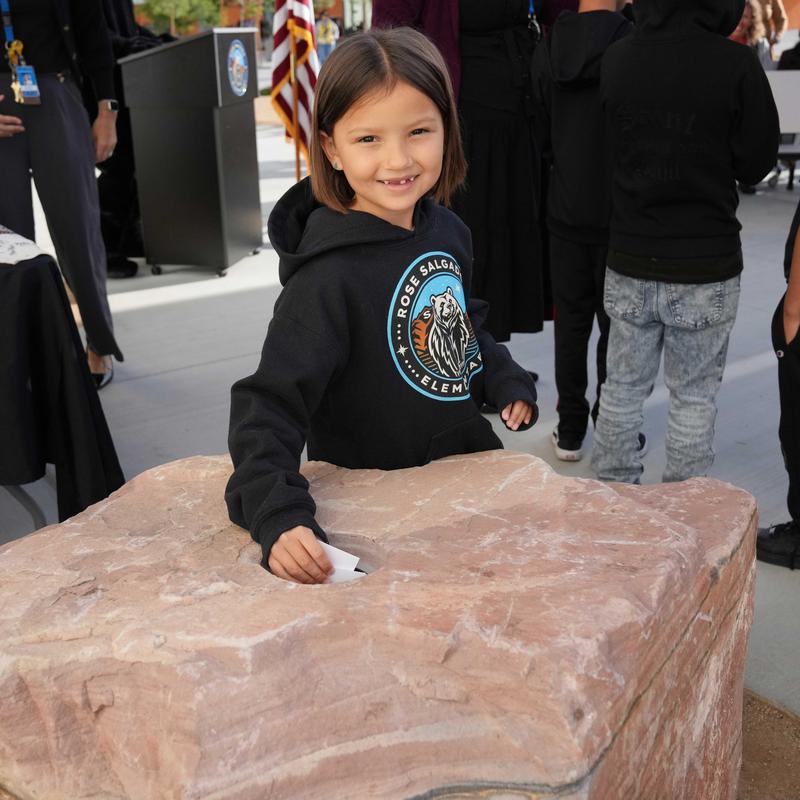 Girl in Rose Salgado sweatshirt putting papers in a time capsule