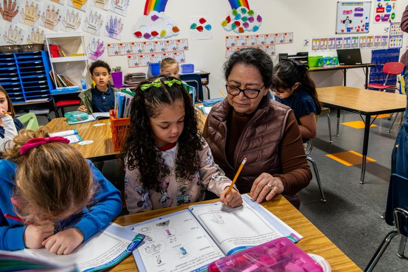 An Arco Iris student and teacher work on an assignment together in their classroom.