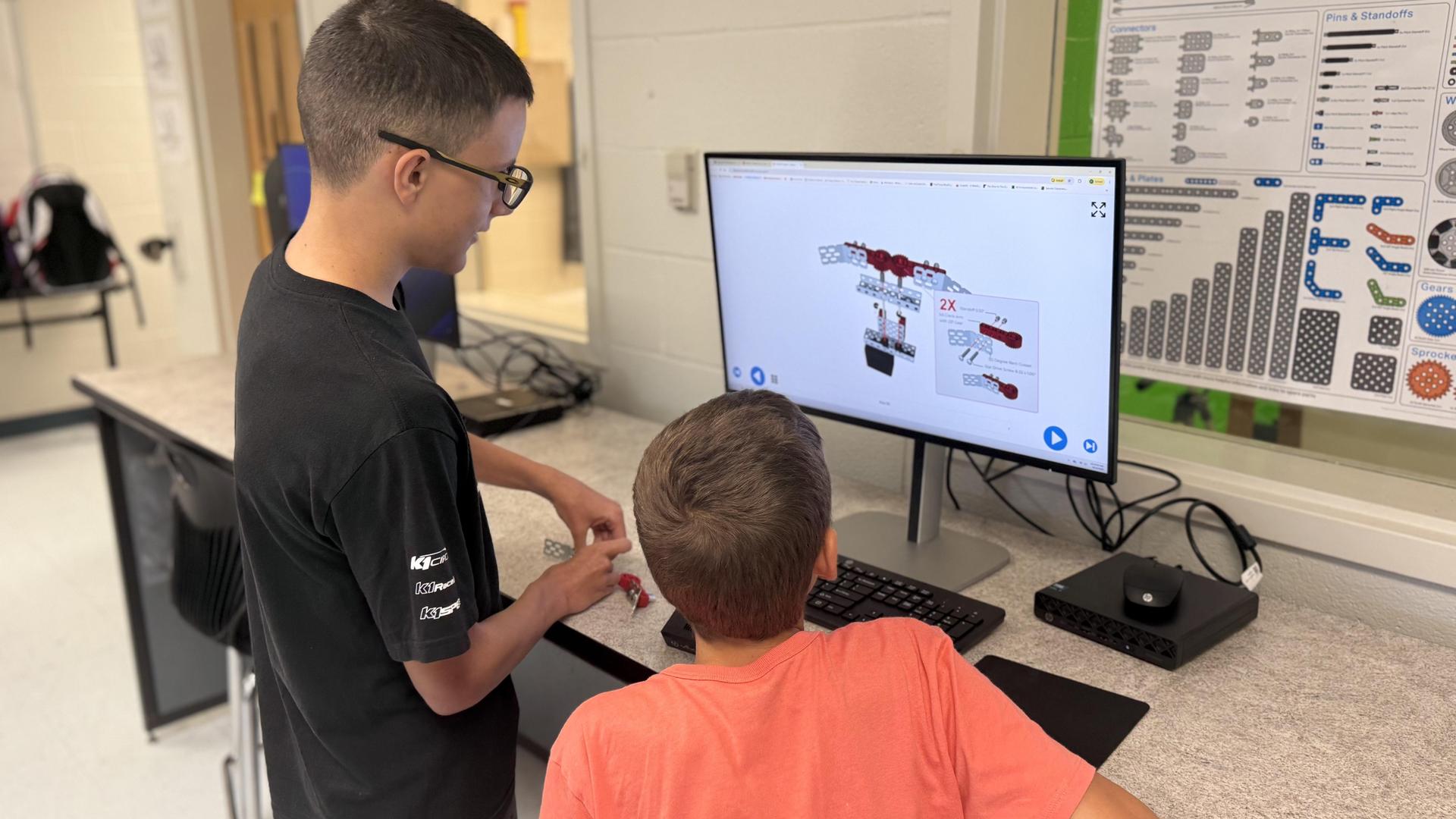 Two children collaborating at a computer, working on a project.